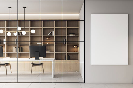 Modern corporate office interior with sleek furniture, bookshelves, and a vertical blank canvas mockup on a clean gray wall background. 3D Rendering