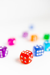 Colorful assortment of dice on white background with focus on red die