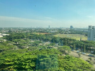 Aerial view of BSD City in Tangerang with lush greenery, modern buildings, and clear blue sky on a bright sunny day.