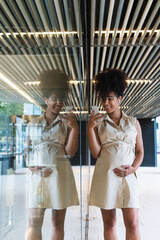 Smiling pregnant woman using smartphone and wireless earphones