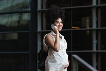 Smiling woman with curly hair talking on smartphone