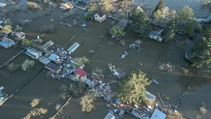 Aerial drone footage showing severe flooding with submerged houses and roads. Wide overhead view of a disaster zone after heavy rainfall, showcasing water damage, extreme weather, and climate-related 