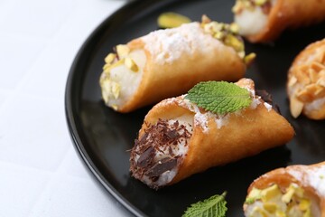 Delicious cannoli with cheese, nuts, powdered sugar, chocolate and mint on white table, closeup