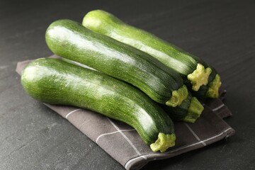 Fresh ripe zucchinis on black table, closeup