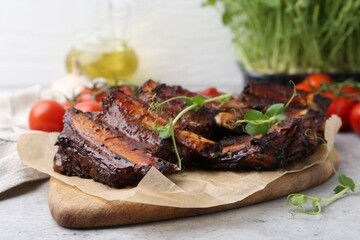 Roasted beef ribs with microgreens on gray textured table, closeup