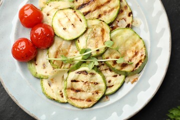 Delicious grilled courgette slices with tomatoes and microgreens on table, top view