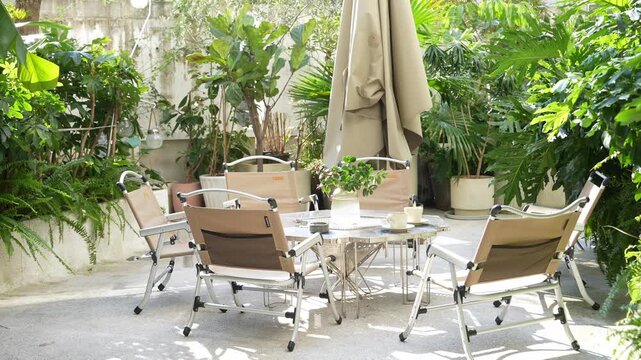 Outdoor patio with lush greenery surrounding a relaxing dining set under a sun umbrella