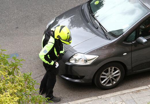 Agente de estacionamiento regulado ser controlador en moto poniendo e imprimiendo multa a coche mal aparcado sin tiquet en la calle en zona azul