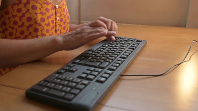 Close-up of hands typing on a black computer keyboard with Cyrillic letters. Person works or studies at desk, concept of technology, communication, office, remote work, and digital lifestyle