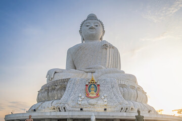 Fototapeta premium White marble Big Buddha of Phuket statue sitting in meditative pose against sky during sunset on the top of high mountain on Phuket island, Thailand. Buddhism in Thailand, sacred architecture