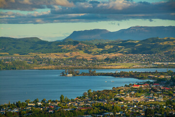 A breathtaking view of Rotorua city nestled beside Lake Rotorua, with rolling green hills and...