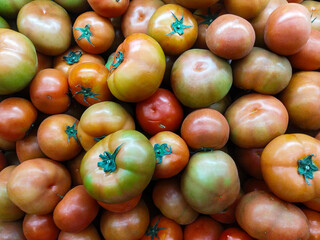 Fresh ripe tomatoes with green stems piled together, showcasing natural colors and textures. Perfect for food, agriculture, cooking, and healthy lifestyle content