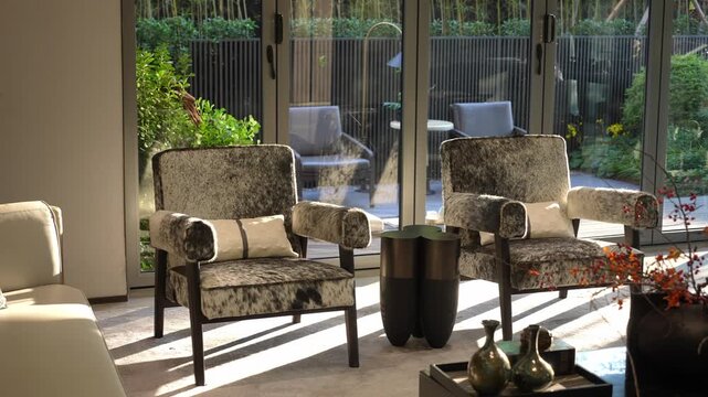 Modern living room with patterned armchairs and fabric sofa beside floor-to-ceiling windows
