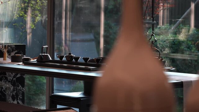 Tea room still life with tea set on wooden table near window, shallow depth of field and blurred foreground