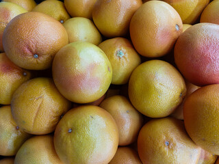Fresh ripe grapefruits piled together showcasing vibrant colors and textured skins, perfect for healthy eating, juice production, and tropical fruit markets