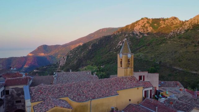 Aerial footage the village of Sainte Agnes, France, nestled in the mountains above the French Riviera, featuring the iconic bell tower of glise Notre Dame des Neiges and traditional terracotta rooftop