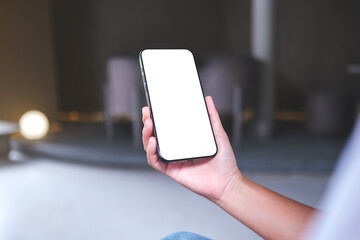 Mockup image of a woman holding and using mobile phone with blank desktop screen in cafe