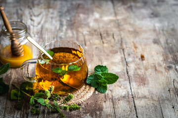 Pfefferminztee in einer Glas Tasse und Honig auf einem rustikalen Holztisch. Erkältung, Kräutermedizin.