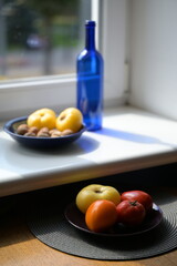 still life with a bottle and vegetables on a sunny windowsill