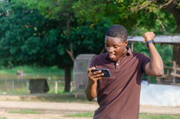 Excited African-american guy focused on smartphone, social media celebrating wining a game, bet