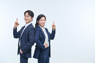 Confident Asian Male and Female Business Colleagues Pointing Up in Office Attire