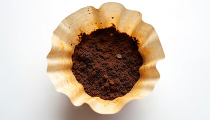 Used paper coffee filter holding dark coffee grounds. Close-up shot of filter, suggesting recycling, composting, waste management solutions. Emphasizes eco-friendly practices for sustainable living,