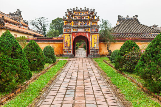 Ornate historic gate with tiled path and manicured garden in Hue Imperial City Vietnam