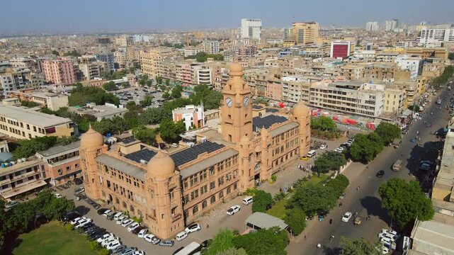 Aerial view of the Karachi Municipal Corporation Building, a sandstone structure with domes and a clock tower, surrounded by lush trees, Karachi, Sindh, Pakistan.