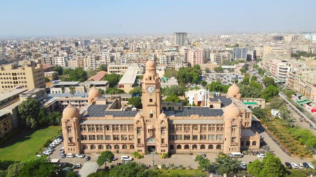 Aerial view of the KMC Building showcasing its colonial architecture amidst lush greenery and bustling city life, Karachi, Sindh, Pakistan.