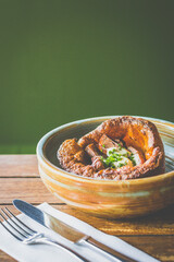 Yorkshire Pudding made with Roast Beef, Gravy, Horseradish served in a ceramic bowl