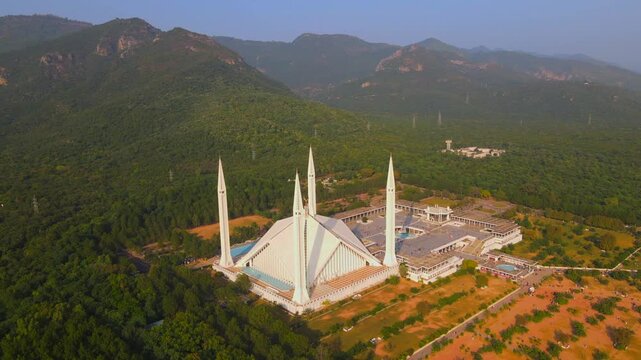 Aerial view of the white marble Faisal Mosque amidst the lush greenery of Margalla Hills, creating a striking contrast, Islamabad, Islamabad Capital Territory, Pakistan.