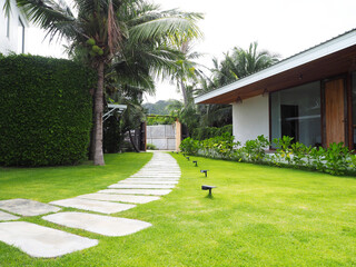 Rectangular concrete or stone garden step path. A serene garden pathway surrounded by lush grass and natural landscaping, creating a resort-style landscape that blends beautifully with nature. Resort 