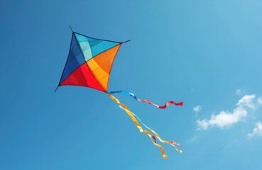 Colourful kite with long tails flies in bright blue sky. Freedom symbol, toy toy, summer outdoor activity, vacation fun. Isolated kite against clean sky background, wind lifts toy.