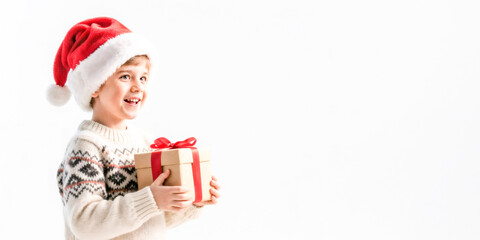 Caucasian young male child in santa hat holding christmas gift with joyful expression