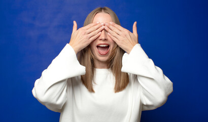 smiling and feeling happy, covering eyes with both hands and waiting for unbelievable surprise