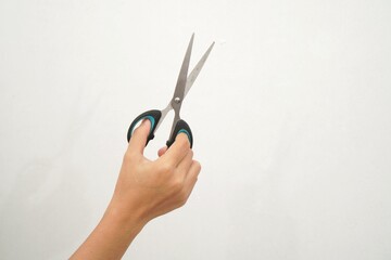 Fototapeta premium Female hands holding black scissors Isolated on white background. Closeup.