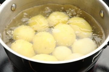 Young potatoes boiling in pot on stove, closeup