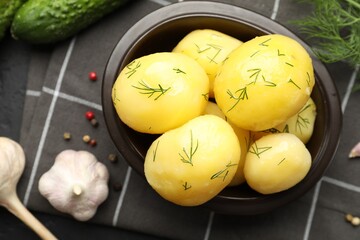 Tasty young boiled potatoes with dill on black table, flat lay