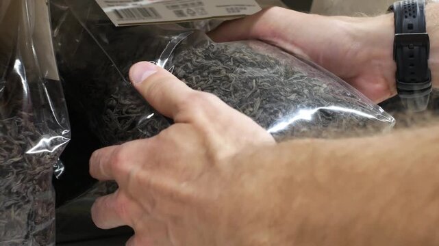 Close-up of male hands taking a packaging of black tea