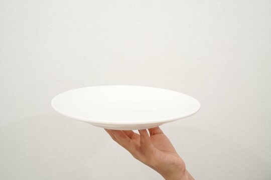 Woman's hand holding an empty plate isolated on white background