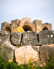 Fototapeta premium Child sits on ancient stone wall
