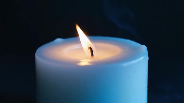 Small blue wax candle burning gently with soft flame and smoke, symbolizing peace, light and focus.