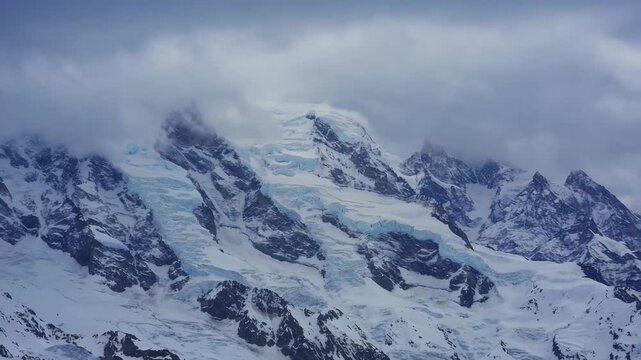 Large snowy mountain slope under cloudy sky with dramatic light, showing wintery alpine landscape and cold atmosphere.