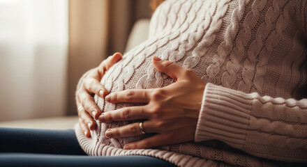 A warm and intimate close-up shot of a pregnant woman sitting comfortably, with her hands resting gently on her belly