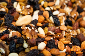 Close-up of mixed nuts. Walnuts, cashews, hazelnuts, raisins and almonds. The shallow depth of field highlights their freshness and nutritional value.