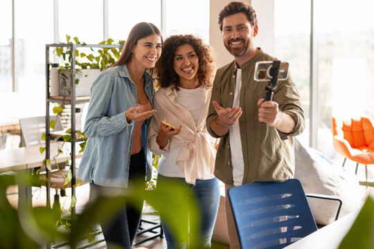 Startup team creating online content with smartphone gimbal in modern office