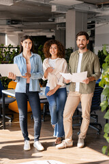Fototapeta premium Startup team posing in modern office with documents and laptop