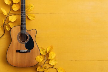 An acoustic guitar sits on a yellow wooden surface adorned with branches of autumn leaves