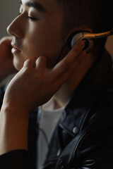 Man enjoying music with headphones in a stylish black jacket.