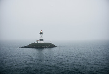 Fototapeta premium Single lighthouse in the water in thick fog